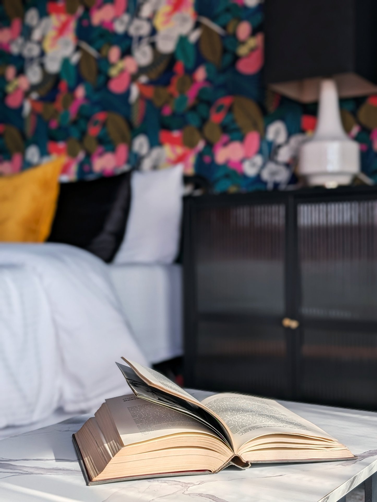 Indigo Studio King at Ocean View Terrace Inn showing bold botanical wallpaper feature wall with mustard pillow and black reeded-glass cabinet